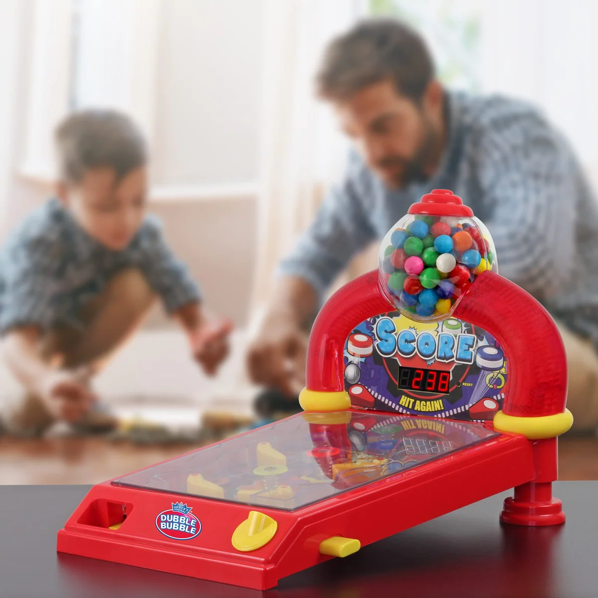 A father and son playing beside a Dubble Bubble pinball gumball machine